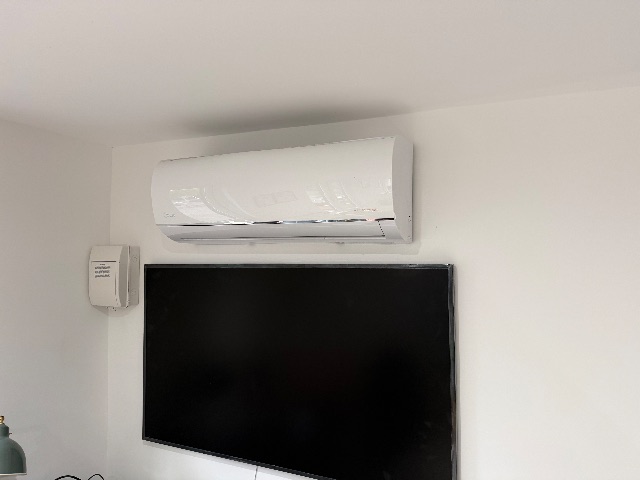 Wall mounted Midea unit above a TV